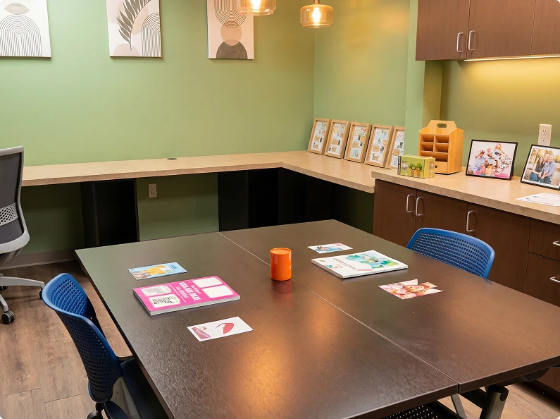 Collaborative learning room with conference table, educational materials, and cabinetry