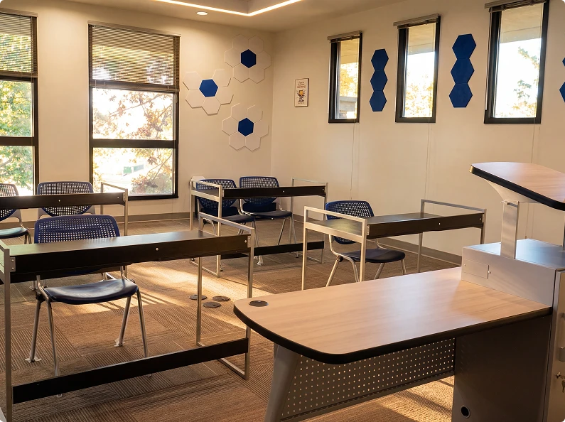 Educational workshop room with instructor station, student desks, and presentation area
