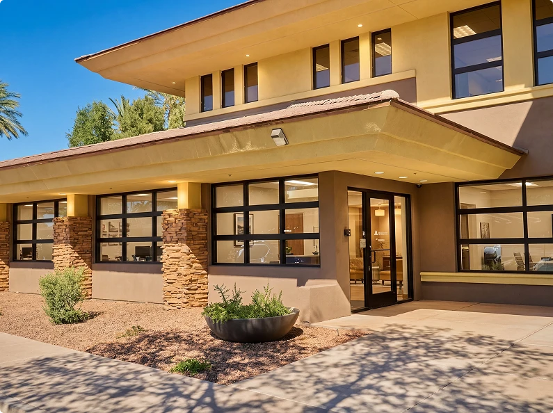 Modern healthcare facility entrance with stone columns and desert landscaping